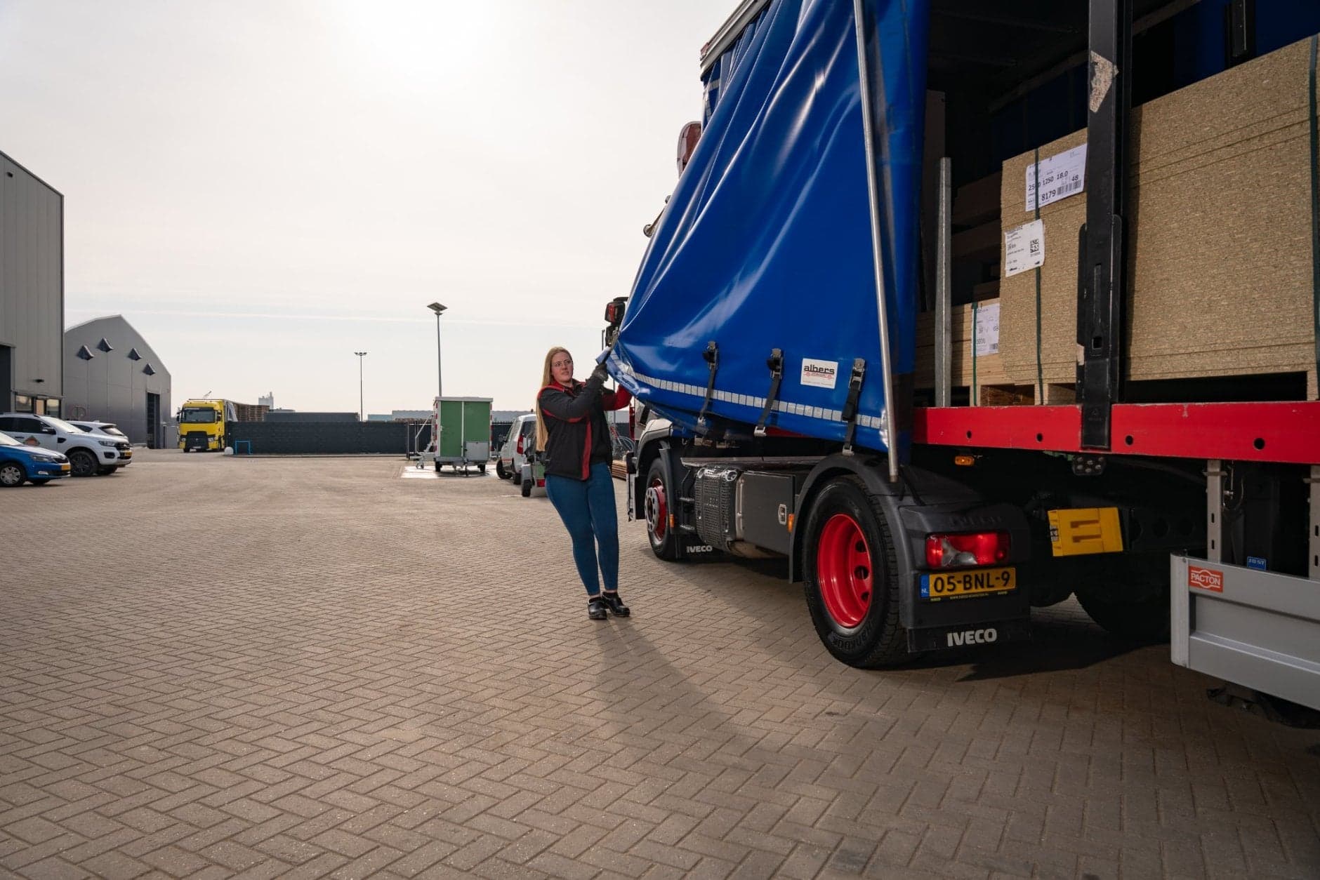 BBL vrachtwagenchauffeur Chantal poseert bij vrachtwagen verwijdert zeil van vrachtwagen