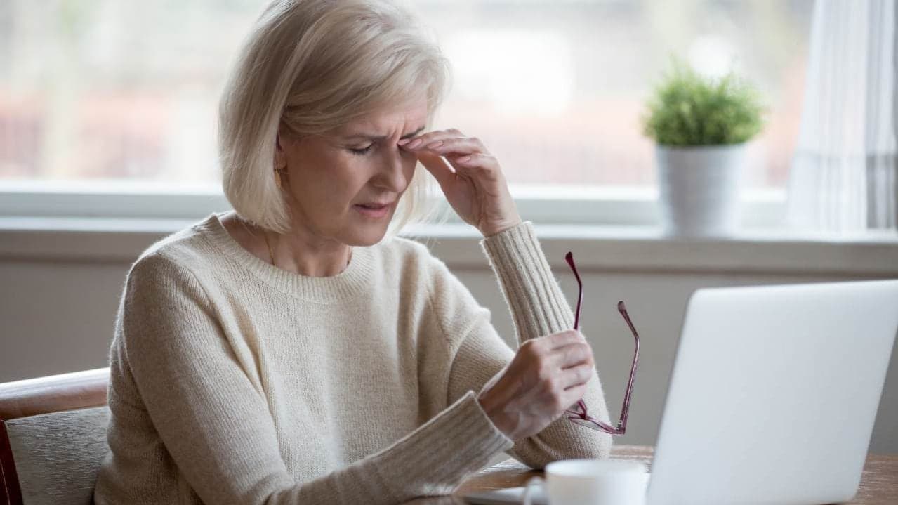 Vermoeide vrouw achter laptop in de overgang