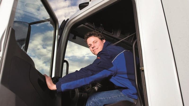 Vrachtwagenchauffeur in cabine met deur open