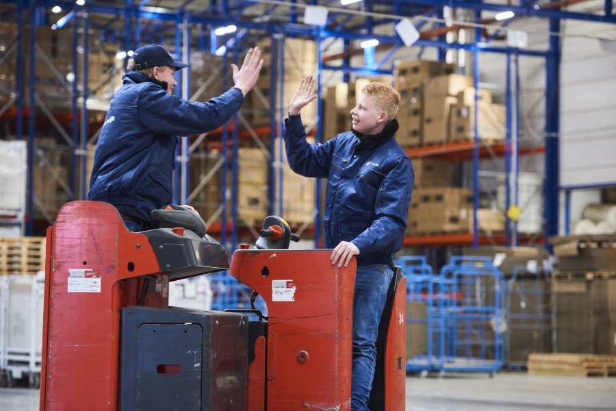 Jongens aan het werk in magazijn, high five