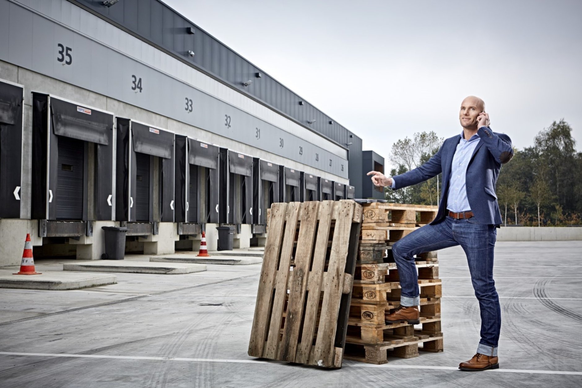 Man naast stapel pallets Sectormonitor transport en logistiek