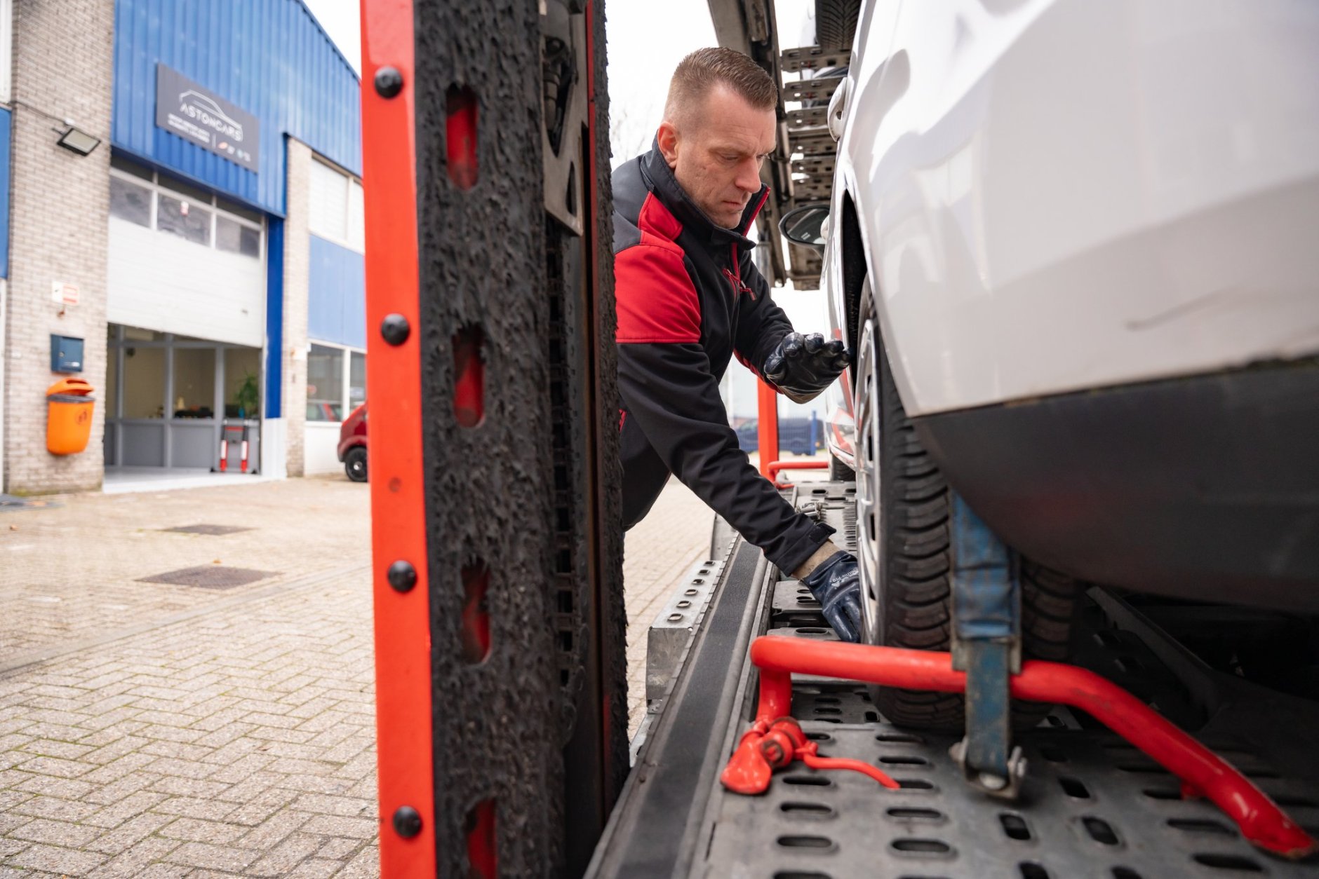 Vrachtwagenchauffeur Leon Boon zet een auto vast met keggen en spanbanden